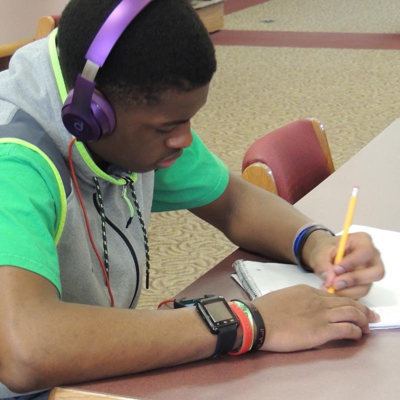 学生戴着耳机在记事本上写字