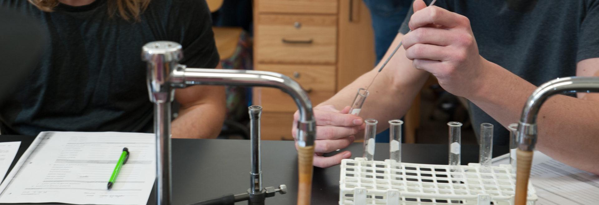 student holding glass test tube in class